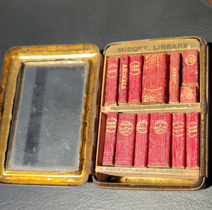 "Midget Library' in original Jahnckes tin, with hinged door     and fitted glass fronted case set in an angled wooden stand. Published by David Bryce & Co.